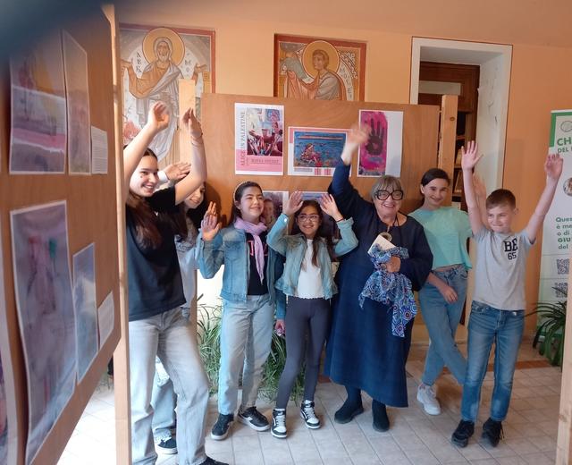 Ragazzi e adulti posano con le braccia alzate davanti alla mostra