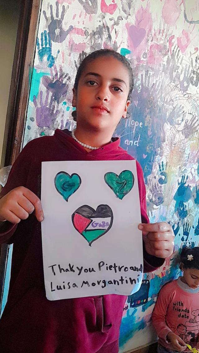 Una bambina di Gaza mostra un disegno con un cuore e la bandiera palestinese